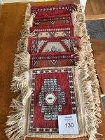 Six handmade Persian fringed carpet squares roughly 12x12 inches each arranged overlapping on a wooden surface