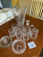 Full view of all crystal and glassware items arranged on a table showing variety including the flared vase, bud vases, candy dishes, and glasses.
