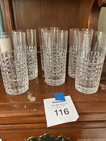 Full set of 8 faceted square cut crystal highball glasses displayed together on a wooden surface.