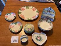 Full view of all items on table showing floral motif ceramic dishes and decorative pieces