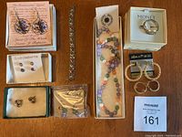 Full lot overview including earrings, bracelet, necklace, pin and ring on wooden surface