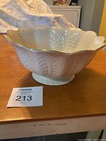 Side view showing the embossed leaf pattern and footed base of the bowl with 24k gold scalloped trim edge.