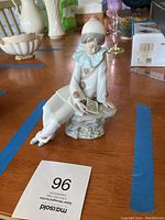 Porcelain Pierrot clown figurine seated reading music sheet from front and side angles.