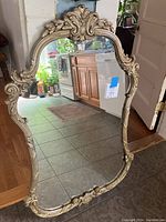 Full view of the ornate vintage mirror showing the carved wooden frame and reflective surface.