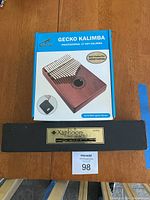 Boxed Gecko Kalimba and boxed Xaphoon pocket saxophone on wooden table.