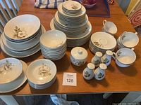 Full view of the assembled lot showing the multiple plates, bowls, serving platters, sugar bowl, salt and pepper shakers, teacups, saucers, and gravy bowl with Ivory Rose floral design and subtle silver trim.