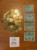 Overview of the lot including four French franc banknotes from 1944 and a group of Irish coins spread beside them on a wooden surface.