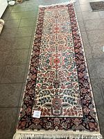 Full length view of the oriental runner on tile floor showing overall pattern and fringed ends