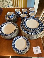 Full grouping of plates, bowls, cups and saucers arranged on wooden table