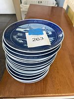 Stacked view of 16 blue and white collectible plates with detailed winter scenes and thematic designs, labeled lot number 263.