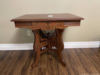 Front angled view of antique wooden table showing carved legs and apron detail