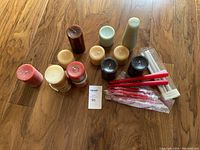 Image showing an assortment of 12 cylindrical candles in various colors and sizes, plus 3 packs of taper candles including red, white, and cream colors.