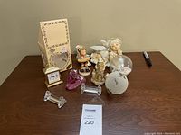 Overall lot showing porcelain figurines, clock with box, glass paperweight, candlesticks, and frosted globe ornament