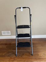 Front view of the 3-step ladder with metal frame and black steps, showing overall condition and structure.