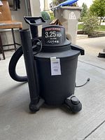 Full view of Craftsman shop vacuum showing black cylindrical tank, hose attached to side, and floor nozzle holder on top of hose with wheels at base.
