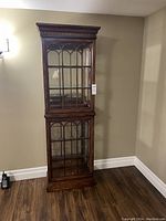 Full view of the two-section curio cabinet against a wall