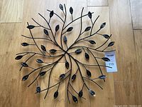 Full view of decorative iron hanging with circular, branch and leaf motif on wooden floor