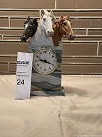 Photo shows horse clock with three horse heads—black, white, and brown—mounted on a marbled stone-like base with a round clock face encased in gold-tone bezel.