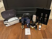 Photo showing Sage white diffuser with grey marble-effect carrying case, black Sage Travel Cloud diffuser in box, and multiple essential oil bottles arranged in front.