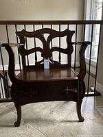 Front view of solid oak entry chair showing carved backrest and curved arms