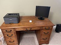 Front view of oak desk with closed keyboard tray and visible drawer and cabinet handles