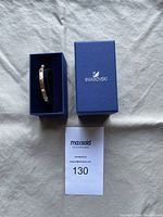 Overview photo of the rose gold-tone Swarovski bracelet inside a blue Swarovski box with the lid off, showing the bracelet placement and outer box with logo.