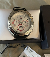 Close-up of Tommy Hilfiger watch face showing white dial, subdials, and tachymeter bezel.