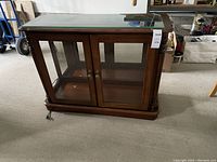 Front view of wooden curio cabinet showing glass double doors and top glass panel.