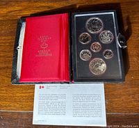Open original red and black Royal Canadian Mint book displaying seven 1978 Canadian proof coins in protective plastic casing and historical information insert.