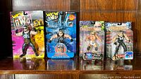 Four 1998 WCW wrestling action figures in original sealed blister packaging on cards, displayed together on wood surface.