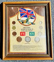 Full view of British World War II coin and stamp collection in oak frame with glass front. Shows the mounted coins and stamps with descriptive text and image of WWII aircraft and Union Jack.
