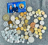 Top-down image of a mixed collection of international coins arranged loosely along with a Royal Wedding commemorative card and coin featuring Prince William and Catherine Middleton.