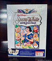 Front view of factory sealed deluxe VHS set box with artwork of Snow White and seven dwarfs and details about bonus features and lithographs.