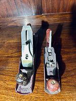 Two vintage hand planes side by side, one Stanley Bailey metal-bodied and one wooden-bodied plane