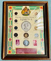 Front view of the framed collection showing all coins and stamps mounted with artwork and text.