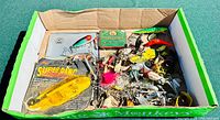 Box of assorted vintage fishing gear including lures, hooks, and tins, showing the variety and quantity of items.