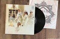 Photo of the Cheap Trick Dream Police LP vinyl record partially pulled out from the album sleeve, showing the band on the album cover and the vinyl disc surface
