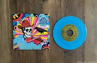 Blue vinyl record displayed alongside colorful psychedelic cover featuring skeleton playing violin and crow, indicating specific edition.