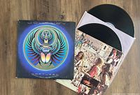Photo showing two Journey 'Captured' vinyl records partially out of album cover and white inner sleeves. Cover front artwork is a blue and purple scarab beetle image.