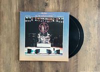 Front cover of the LP showing stage lights, drum set and the Rush logo, sleeve shows minor surface wear but overall excellent condition.