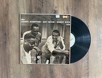 Top-down view of the vinyl record partially out of its sleeve showing the light blue Columbia label and the sleeve cover photo of the trio.