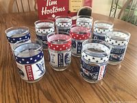 Front view showing the ten Apollo mission collectible drinking glasses arranged on a table, with visible star-spangled design bands.