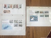 Four Guernsey First Day Covers displayed on white sheets in clear plastic sleeves, showing various postage stamps and postmarks.