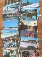 Top view showing a spread of colorful postcards depicting various landscapes and cityscapes including mountains, gardens, historic buildings, and floral scenes.