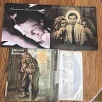 Three LP record albums on a wooden floor: Steve Winwood's Back in the High Life, Pete Townshend's Empty Glass, and Jethro Tull's Aqualung.
