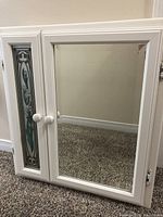 Medicine cabinet front view showing mirrored door and decorative floral glass panel door.