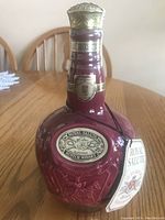 Close-up front view of the burgundy ceramic decanter bottle, embossed label, and attached Royal Salute tag.