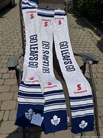 Three Toronto Maple Leafs scarves laid out on an outdoor chair, showing the full length with 'GO LEAFS GO' text, team logos, and Scotiabank branding.