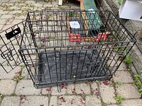Full view of the black metal wire dog crate with open door showing removable plastic tray inside.