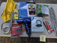 Photo showing all lot items arranged on ground including the Onn Indoor HDTV antenna box, Revlon blow dryer, yellow tarpaulin bag, blue plastic sheet, zip ties, cable, and form protection pipes.